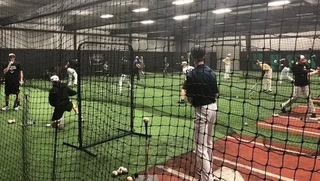 A full team hitting session running across the indoor cages