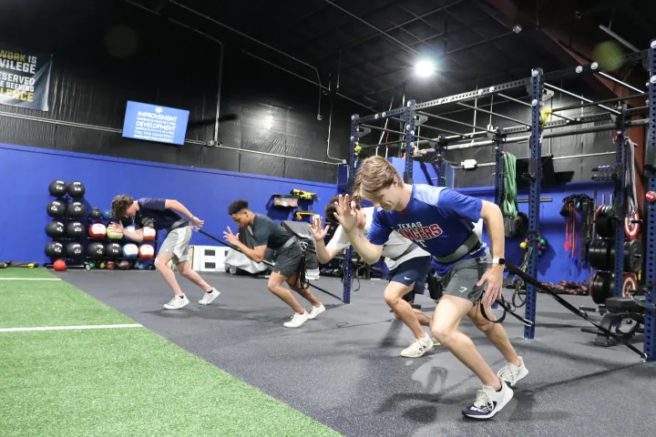 Athletes running resisted sprint starts on the turf lane