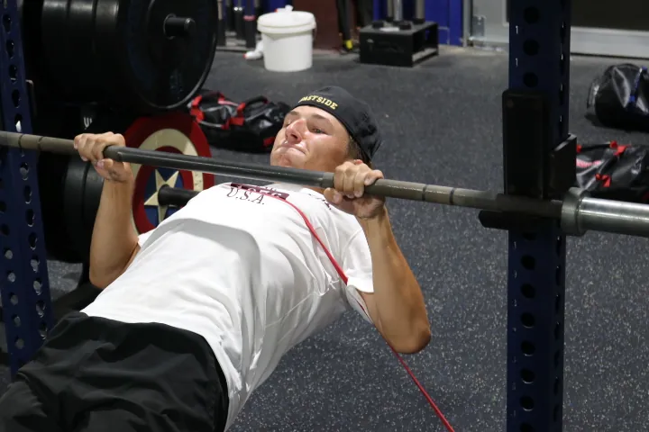 An athlete benching in the weight room