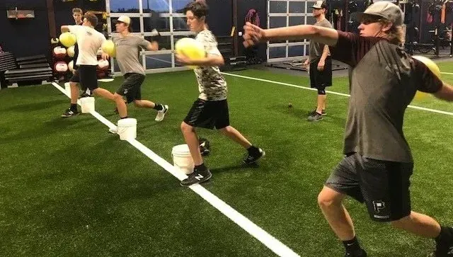 Athletes doing medicine-ball rotational throws on the turf